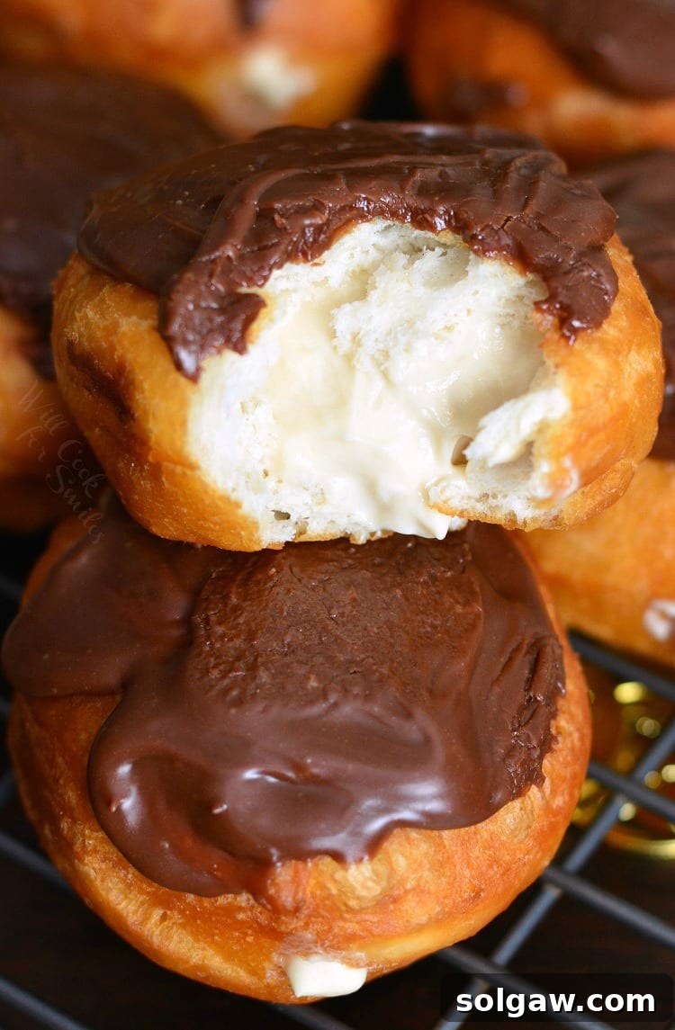 Delicious Bailey's Cheesecake Doughnuts on a cooling rack with a bite taken out of one, revealing the creamy filling.