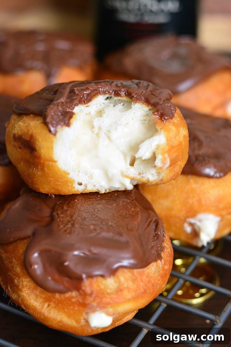 A Bailey's Cheesecake Doughnut with a bite taken out, showcasing the creamy filling and chocolate ganache.