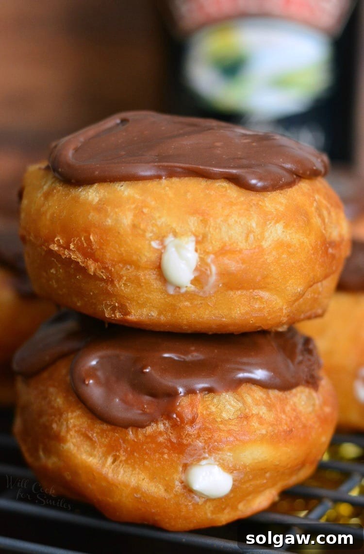 Stacked Bailey's Cheesecake Doughnuts on a cooling rack, showcasing their fluffy texture and delicious topping.