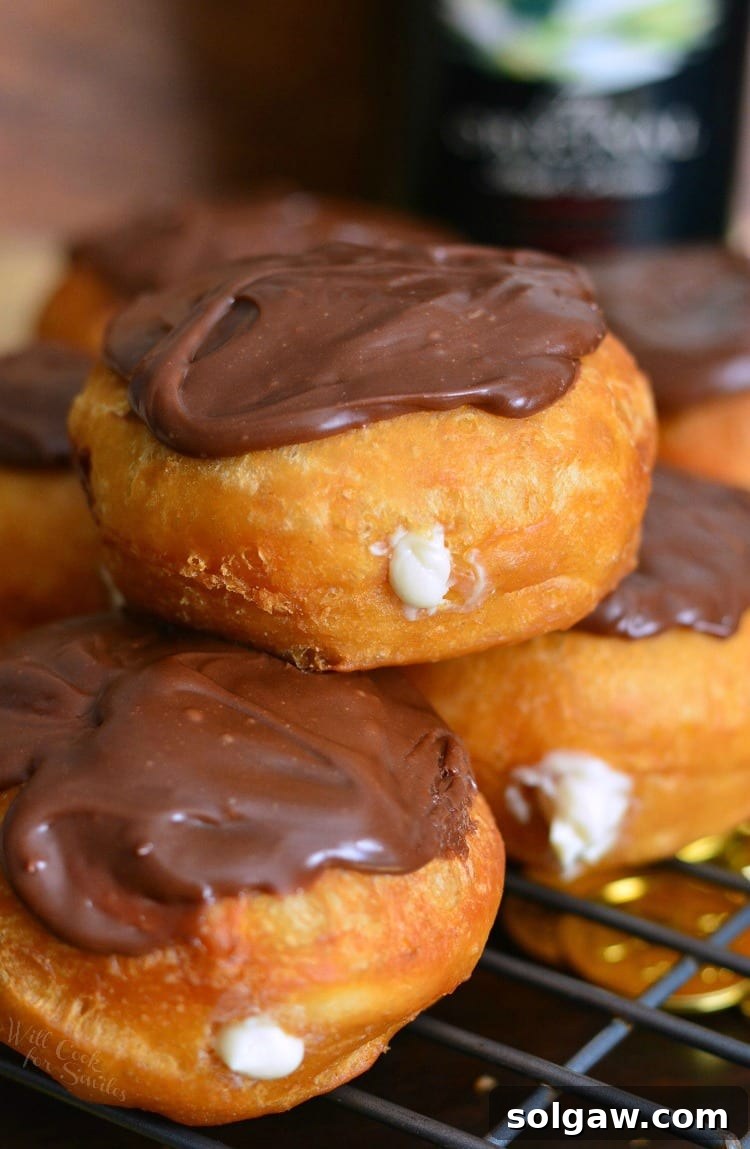 Three Bailey's Cheesecake Doughnuts stacked on a cooling rack, showing their exquisite topping and fluffy texture.