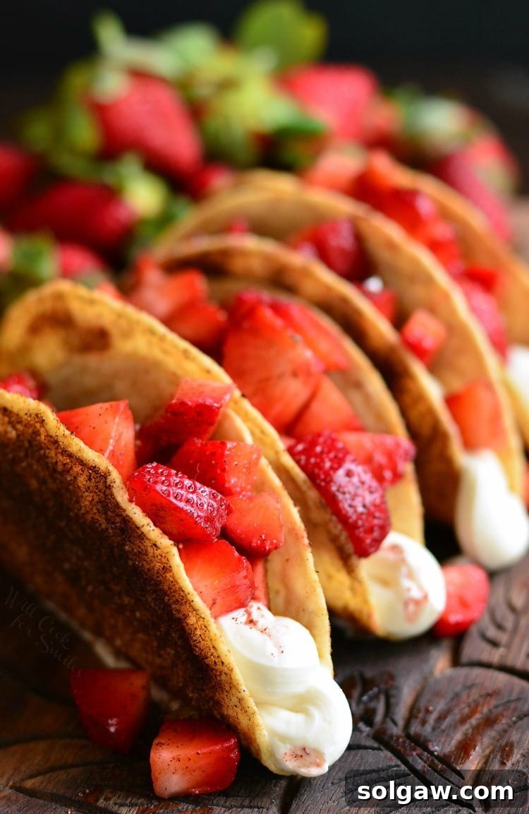 Delicious Cinnamon Strawberry Cheesecake Dessert Tacos artfully arranged on a rustic wooden cutting board, showcasing their golden shells and vibrant red filling.