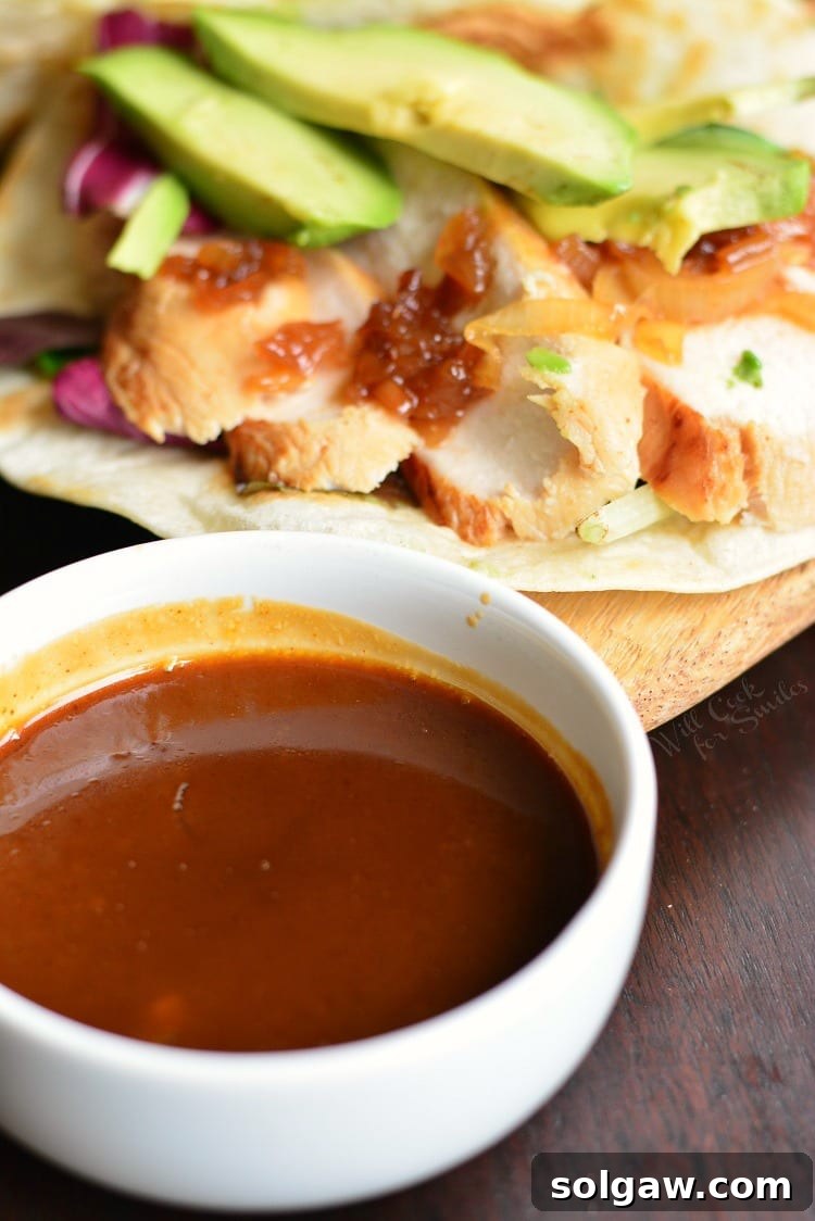 A delicious chicken taco artfully arranged in a soft tortilla, accompanied by a small bowl of the signature sweet and spicy tequila sauce.