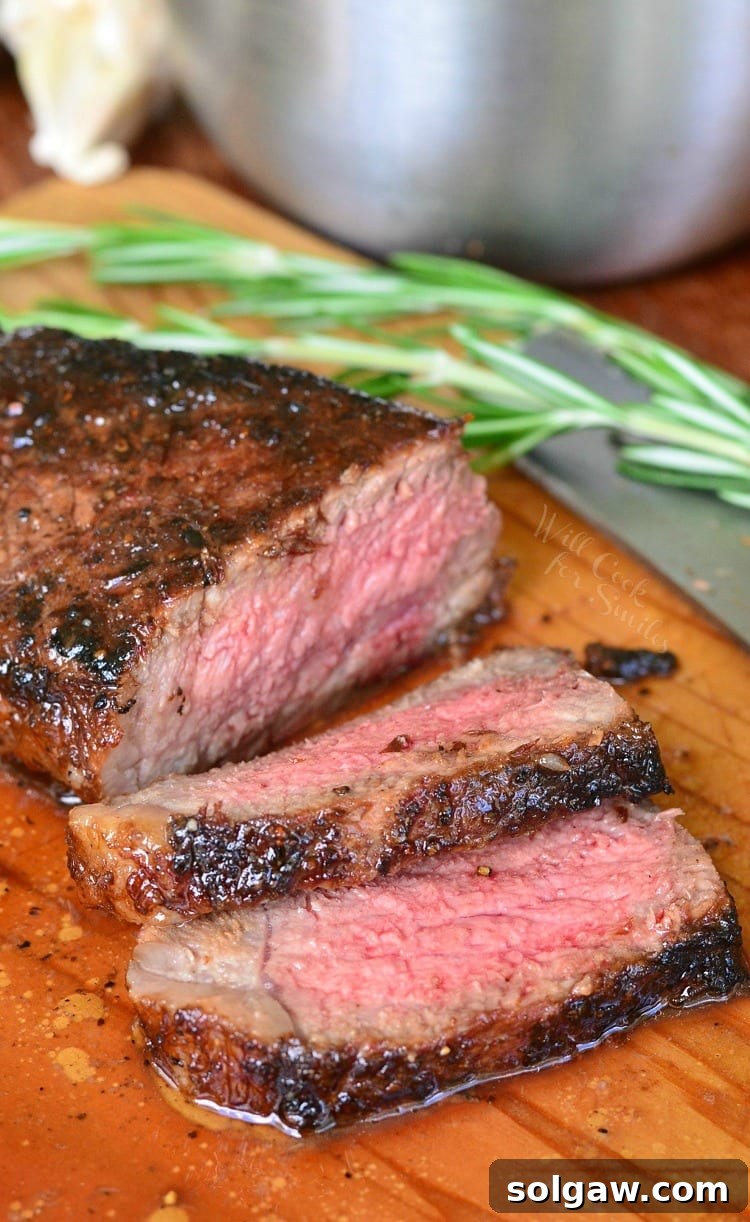 Steak on a wood cutting board with a sprig of rosemary