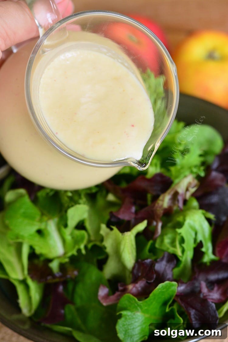 pouring homemade Apple Vinaigrette over a salad