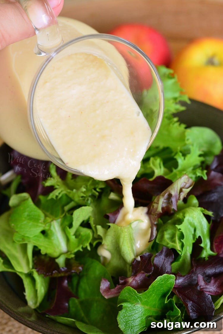 pouring homemade Apple Vinaigrette over a salad