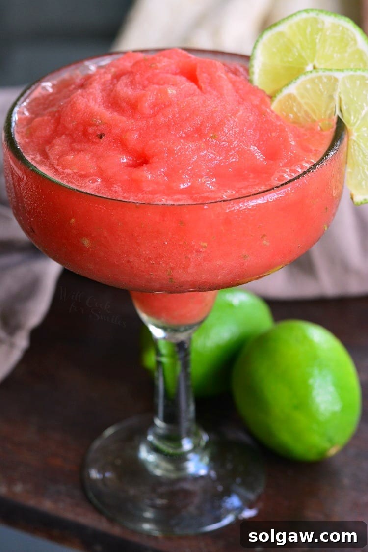 Vibrant frozen watermelon margarita in a classic glass, garnished with a fresh lime wedge on the rim.