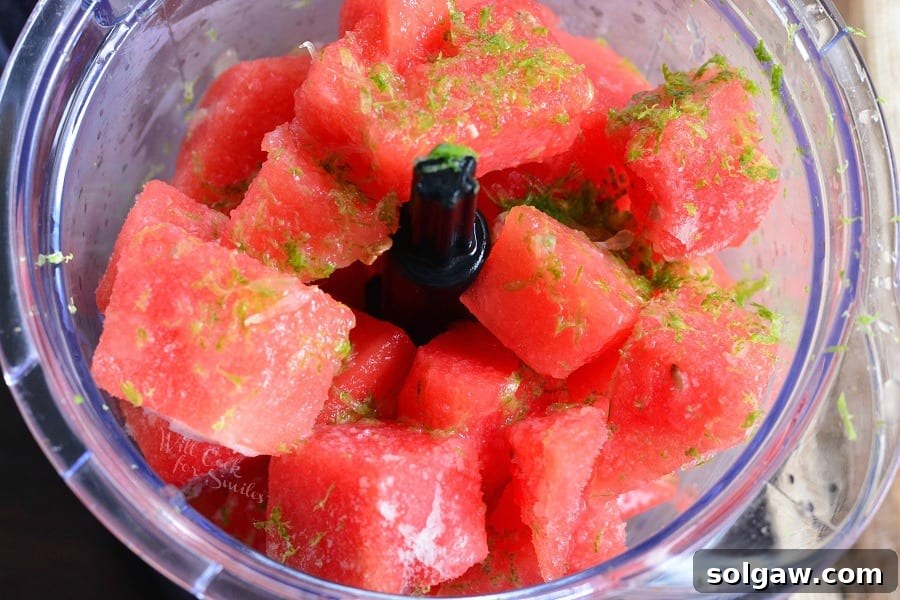 Freshly cut watermelon chunks, vibrant green limes, and a bottle of tequila, ready for blending into a delicious frozen margarita.