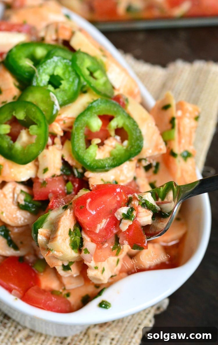 A fork scooping a portion of Spicy Mexican Chicken Salad from a serving bowl, highlighting the fresh ingredients