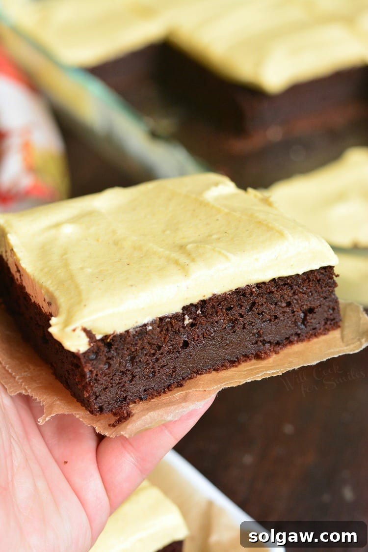 Frosted Pumpkin Brownies held in hand, showing the glossy frosting and brownie texture.