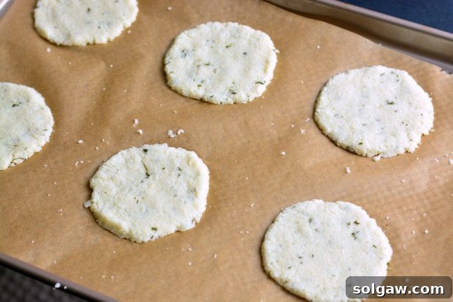 Cauliflower dough pressed into thin disks on parchment paper, ready for baking.