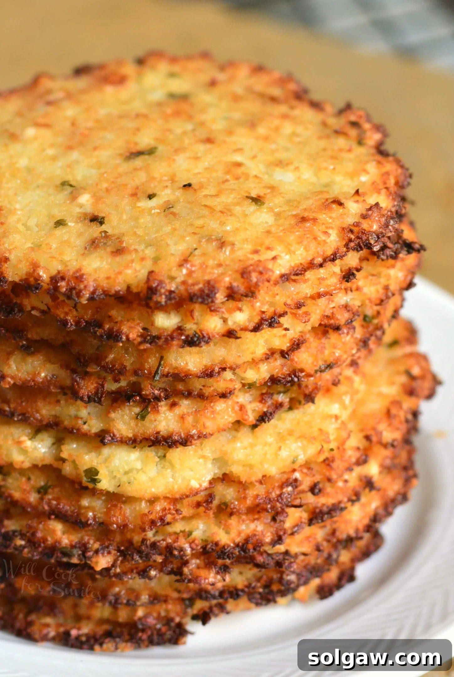 Hand holding a single golden-brown Cauliflower Parmesan Crisp, highlighting its crunchy texture.