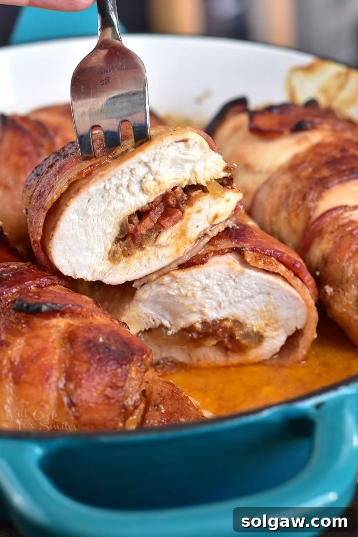 Cooked Bacon Wrapped BBQ Stuffed Chicken Breasts in a pan, with one chicken breast sliced in half showing the delicious filling, ready to serve.