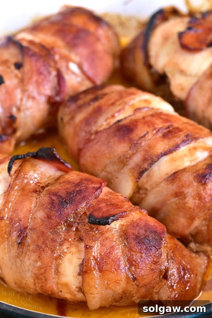 A collection of cooked Bacon Wrapped BBQ Stuffed Chicken Breasts in a pan, showcasing their golden-brown, crispy bacon exterior, ready to be served.