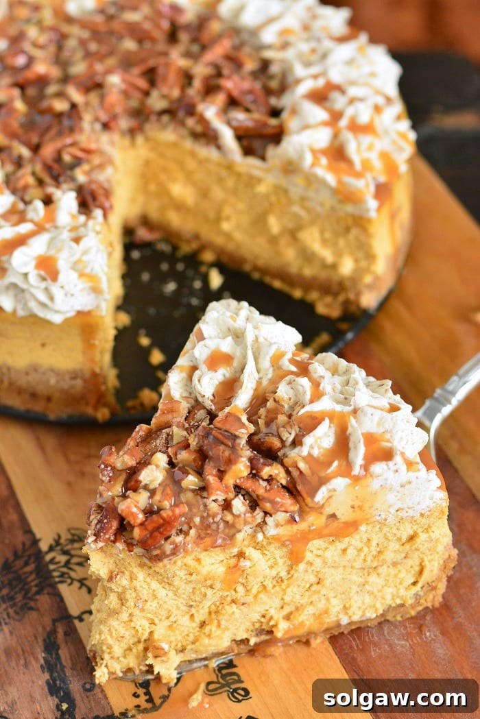 A close-up of a Pecan Caramel Pumpkin Cheesecake slice with the full cheesecake in the background