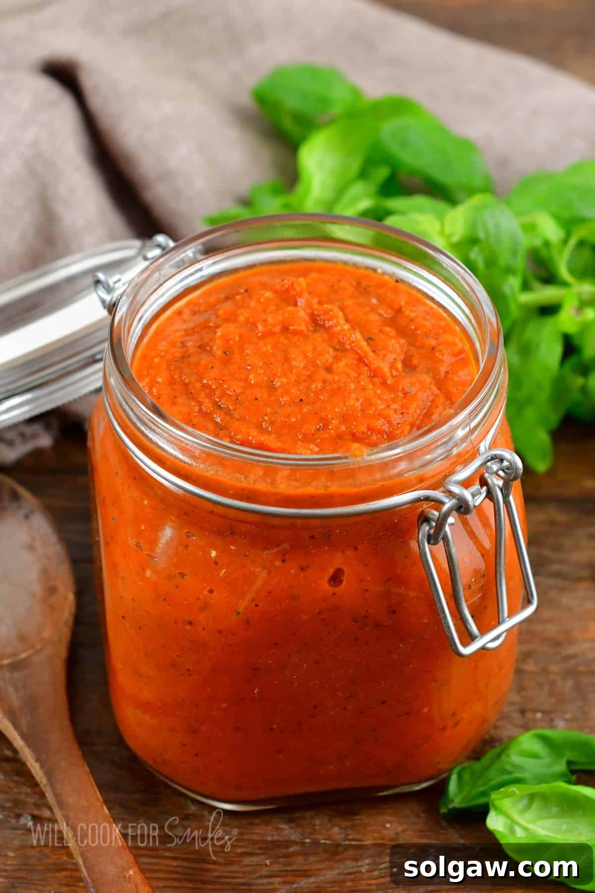 A glass jar of homemade spaghetti sauce, perfectly smooth and rich, sitting on a rustic wooden surface, ready for storage or serving.