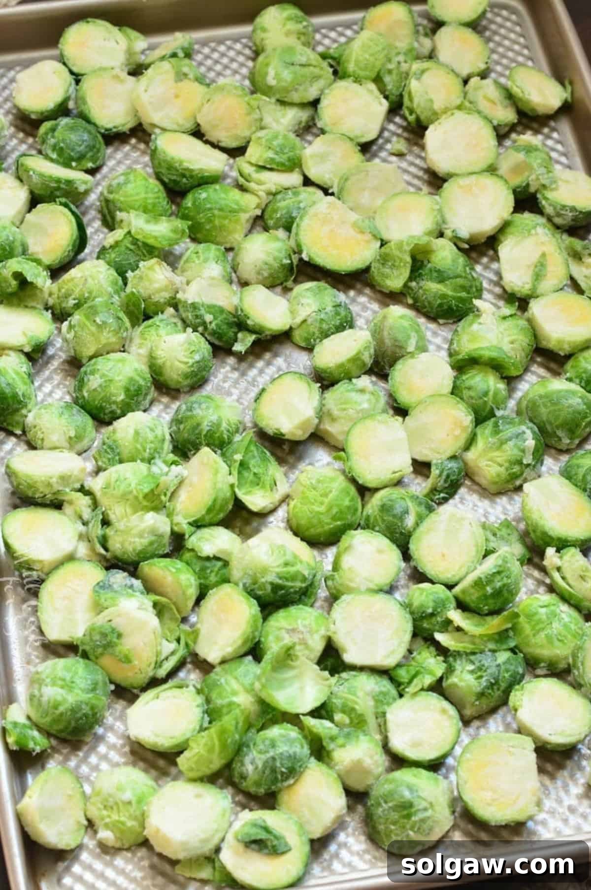 Uncooked brusssels sprouts on a baking sheet.