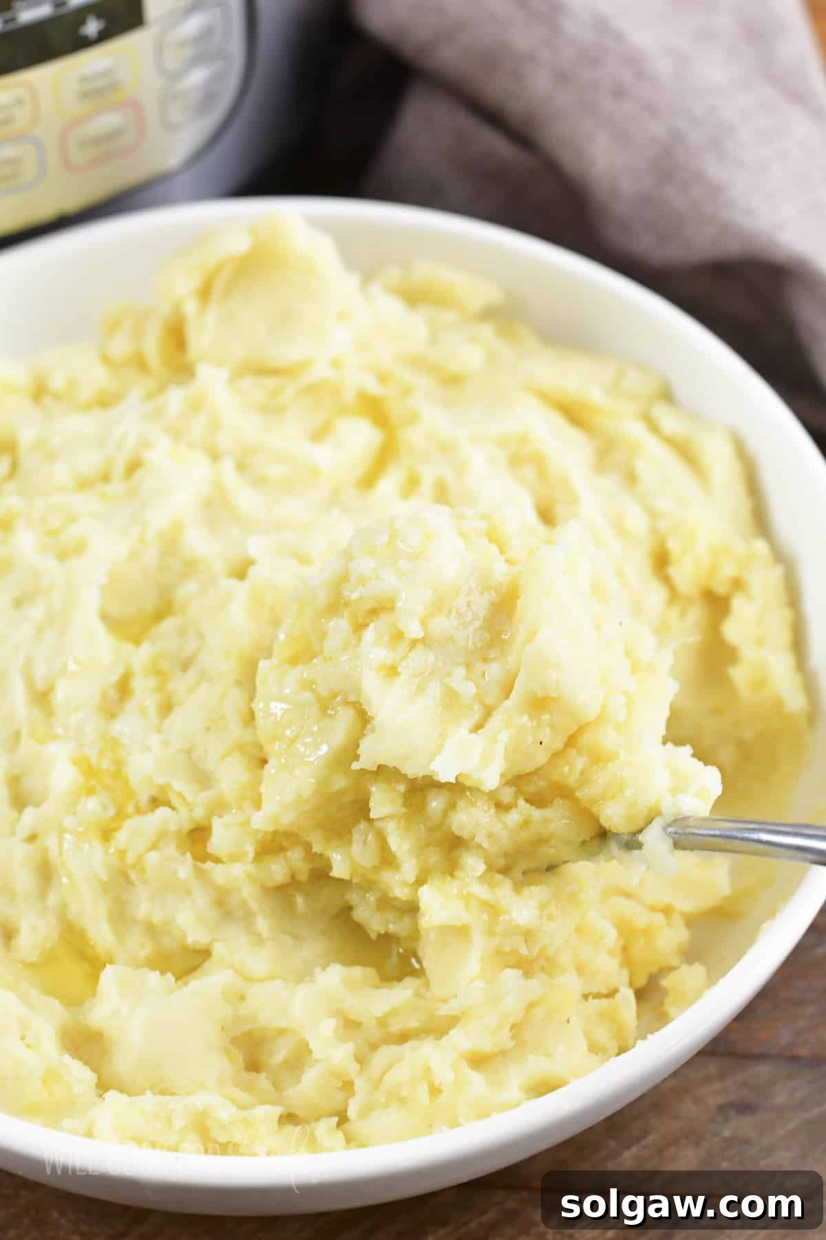 A serving of perfectly mashed potatoes, warm and inviting, scooped from a white bowl, ready to be enjoyed.