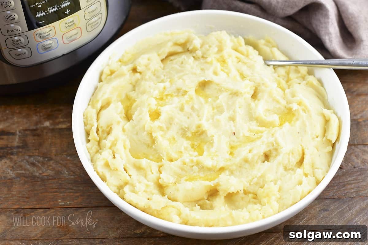 A close-up of creamy mashed potatoes served in a bowl, glistening with a dollop of melted butter on top, ready to be savored.
