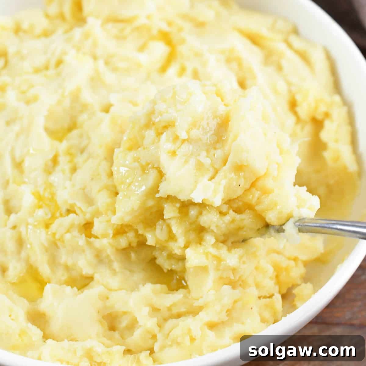 A closeup of a spoonful of creamy Instant Pot Garlic Mashed Potatoes, ready to be served.