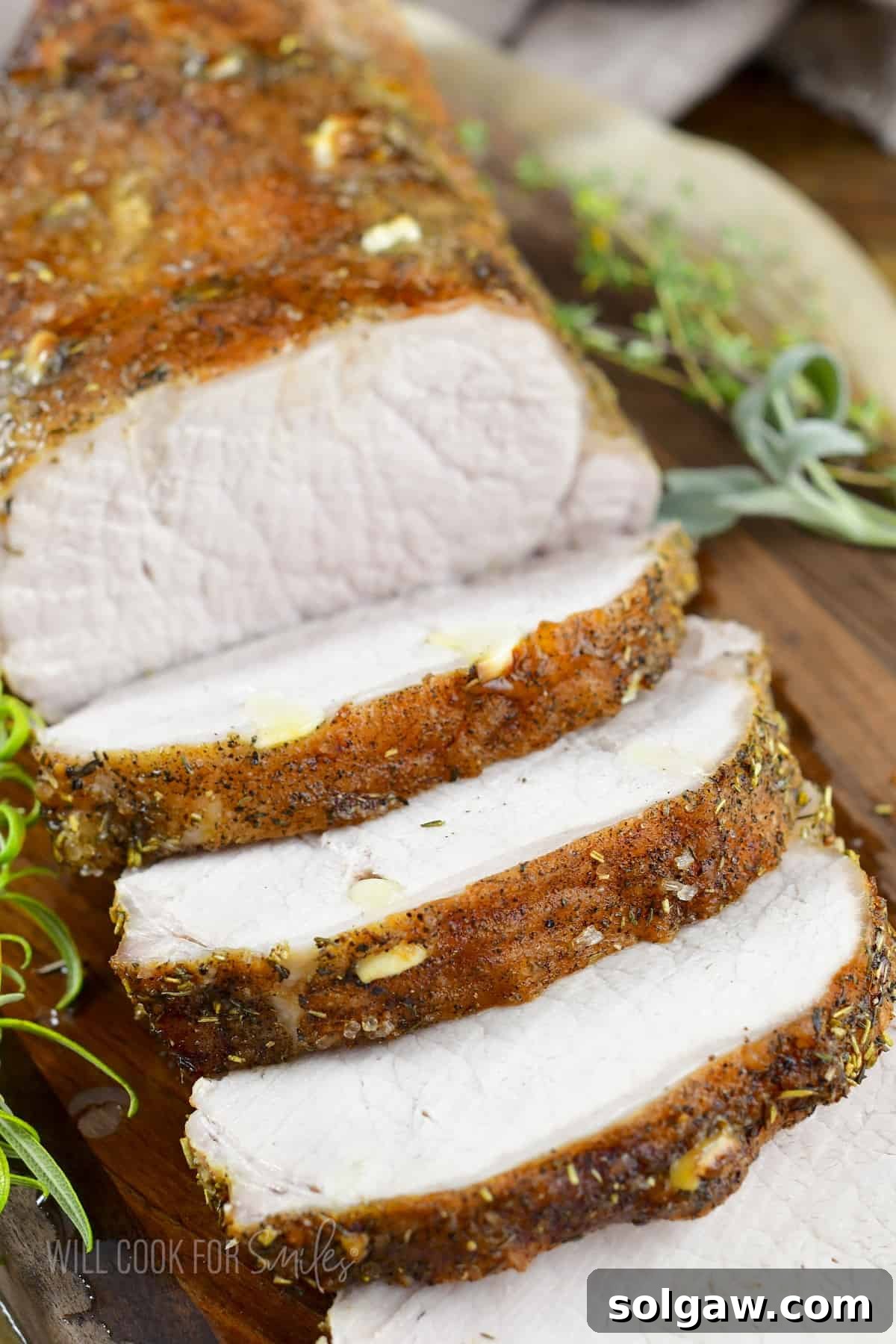 Aromatic Garlic Pork Loin 2 sliced roasted garlic pork loin on the board and sprig of rosemary.