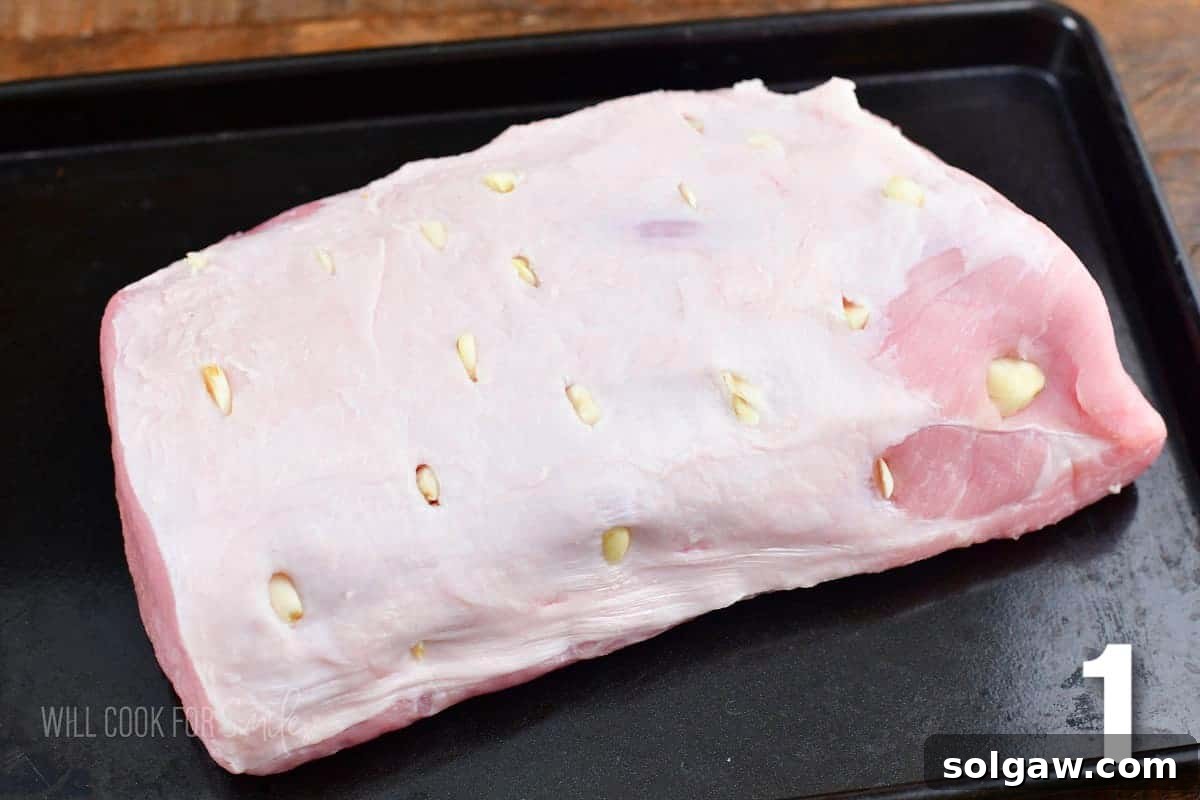 Aromatic Garlic Pork Loin 4 pork loin with garlic slices inserted into slits in the meat on the baking sheet.