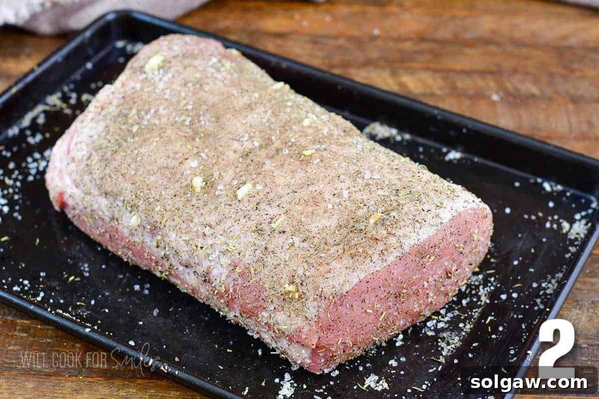 Aromatic Garlic Pork Loin 5 seasoned uncooked pork loin on the baking sheet.
