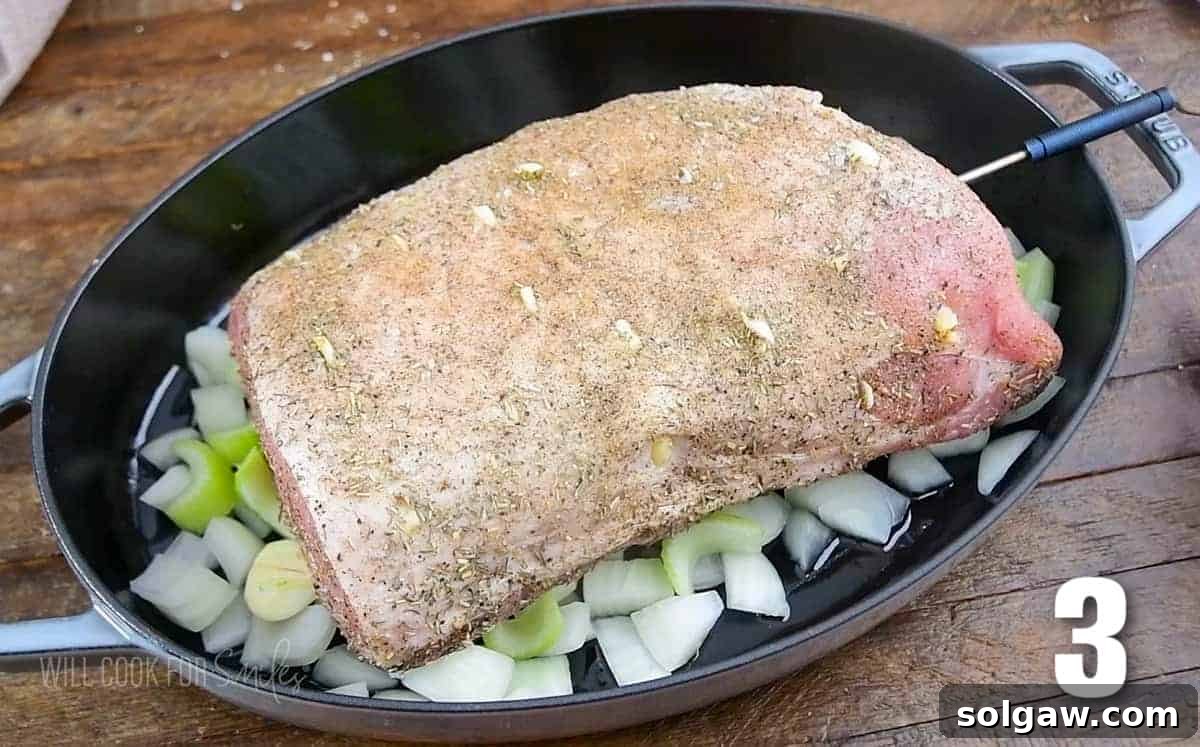 Aromatic Garlic Pork Loin 6 seasoned uncooked pork loin resting on the chopped vegetables in the roasting pan.