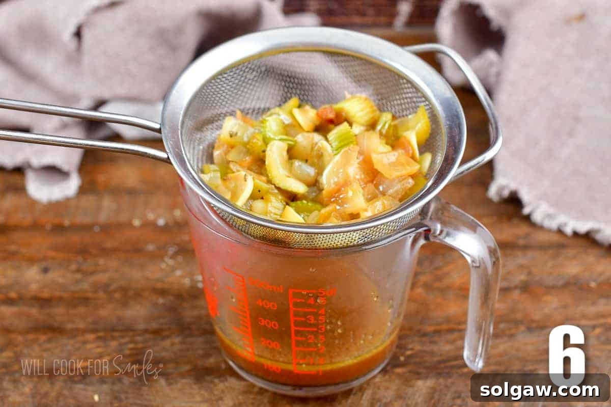 Aromatic Garlic Pork Loin 9 straining the pan juices through mesh strainer into a measuring glass.