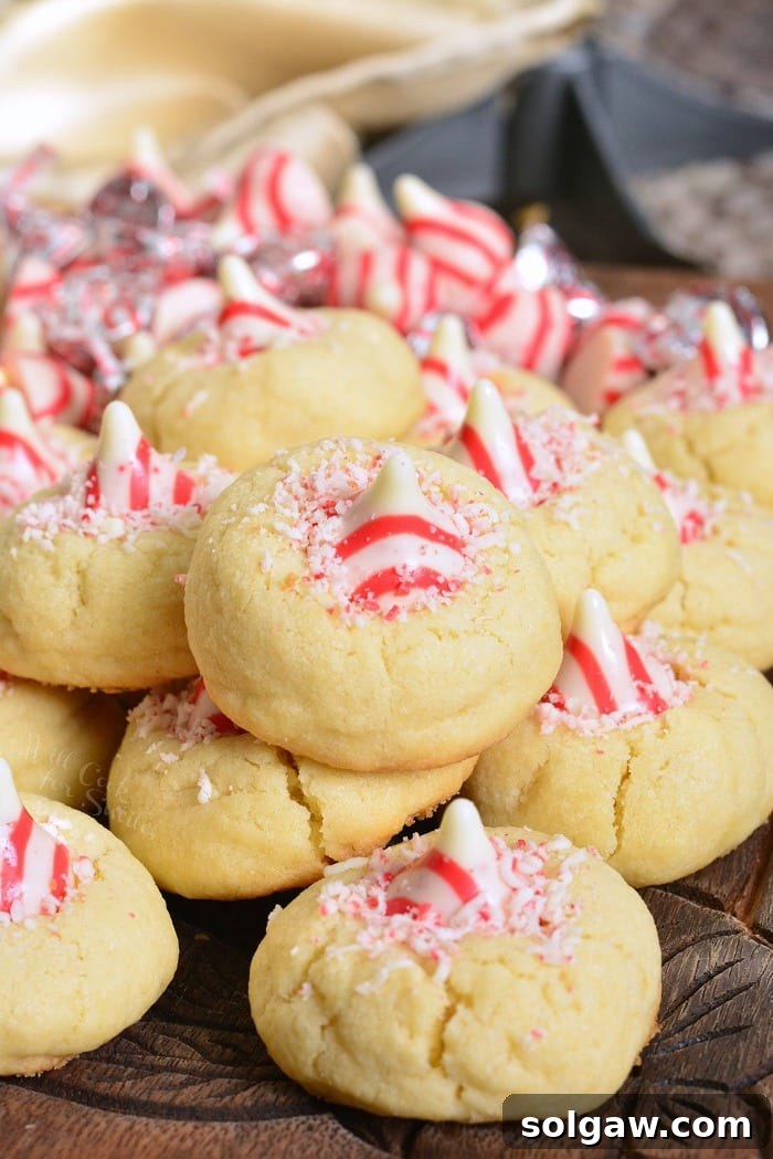 A full view of the rustic wooden table with several plates of Peppermint Thumbprint Cookies, and other holiday decorations.