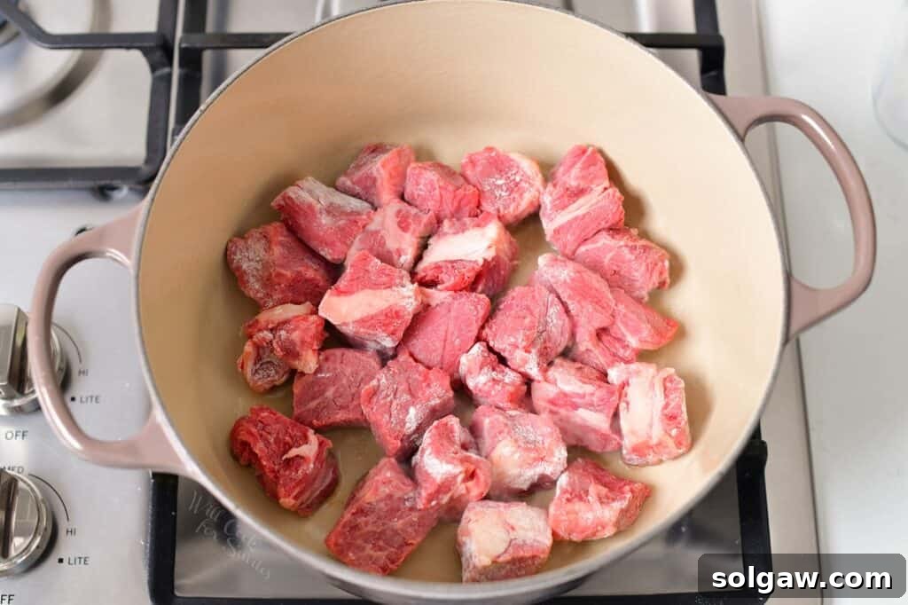 Beef pieces being seared to a golden brown in a hot Dutch oven