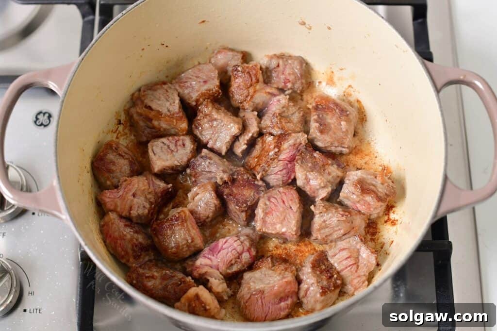Perfectly seared beef cubes resting in a Dutch oven on the stove, ready for the next step