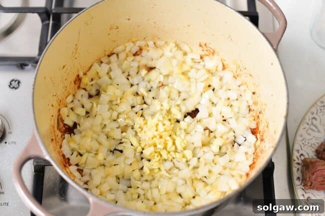 Onions and garlic sautéing in a Dutch oven, releasing their aromatic flavors