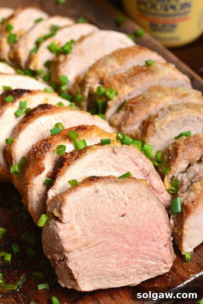 sliced pork tenderloins stacked side by side on a serving with with chives on top.
