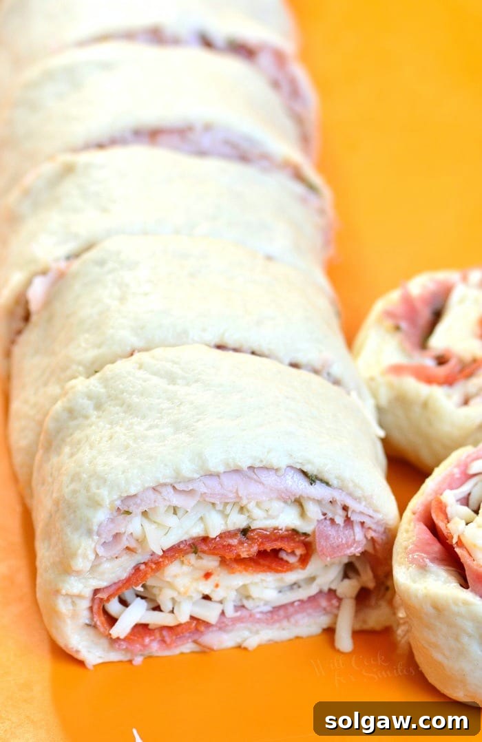 Uncooked Italian Sub Pinwheels neatly arranged on a cutting board, ready for baking.