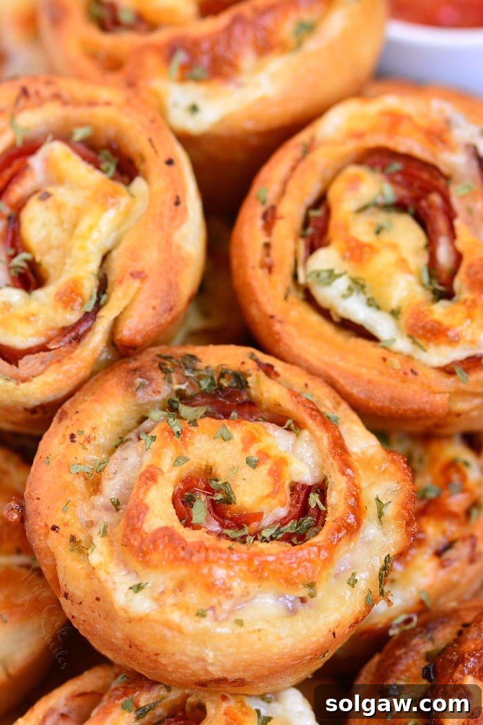 Italian Sub Pinwheels elegantly stacked on a white plate, showcasing their layers.