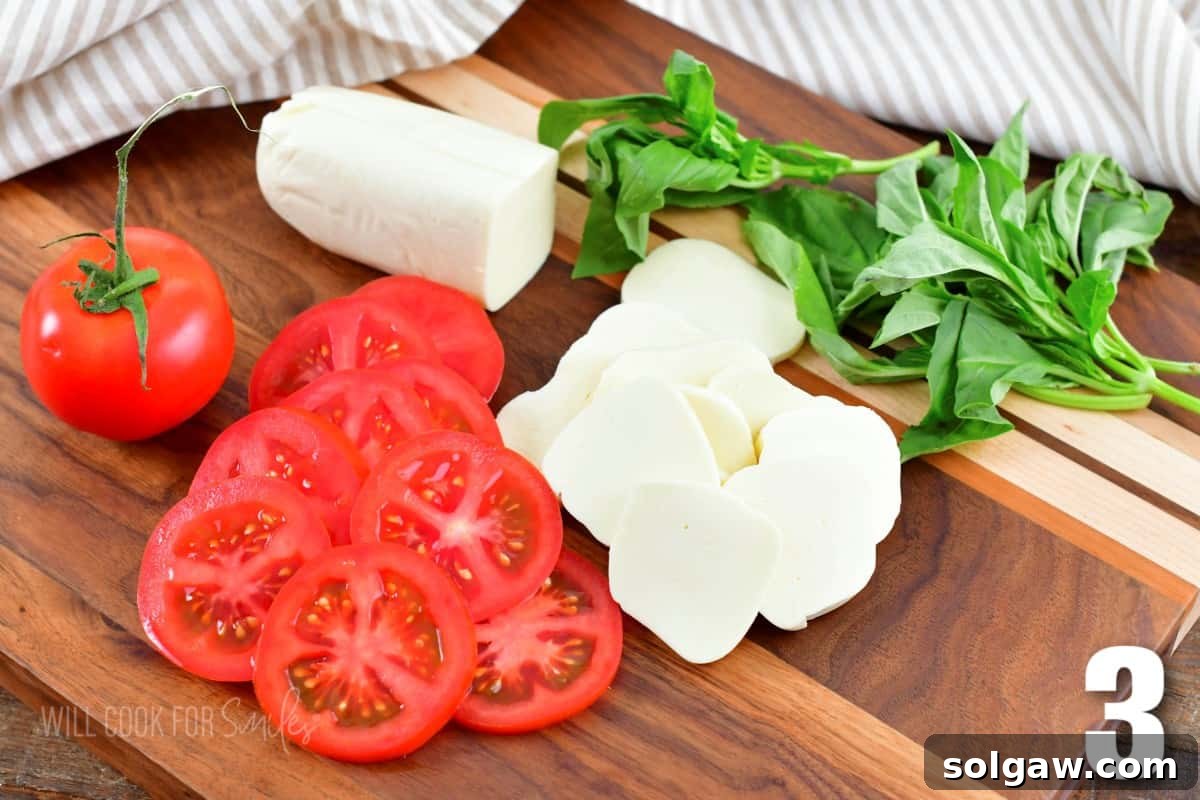 sliced tomatoes and sliced mozzarella cheese on cutting board next to basil.