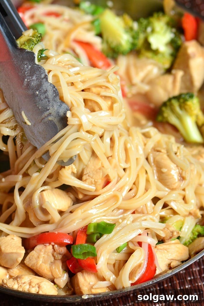 Sesame Chicken Noodles in pan lifting some out with tongs 