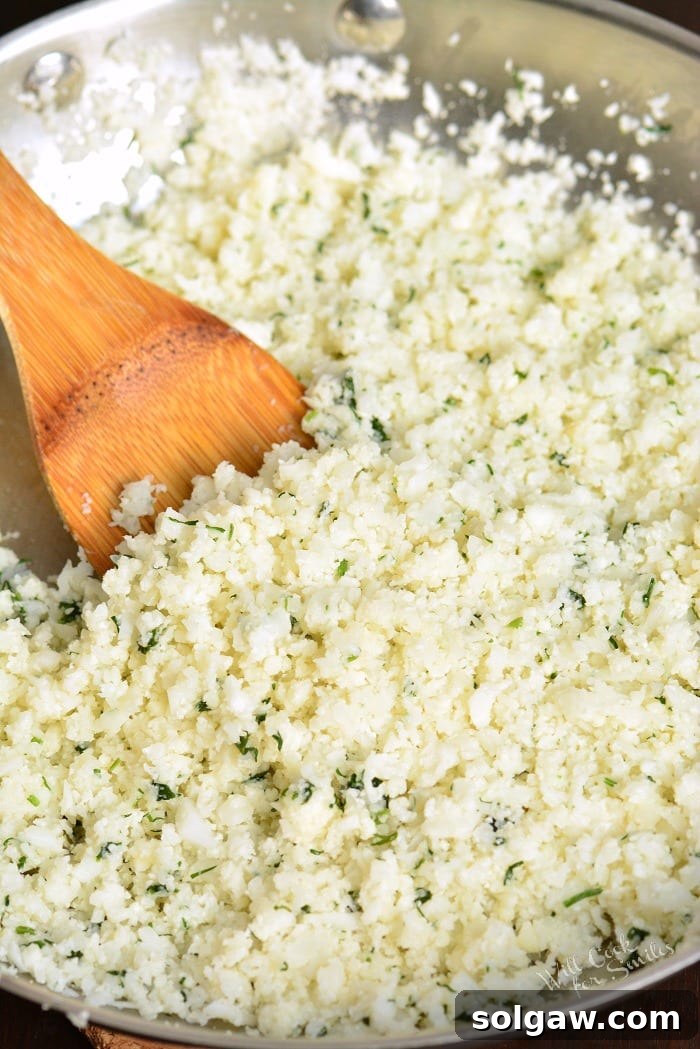 Cauliflower rice with a metal bowl and a wooden spoon 