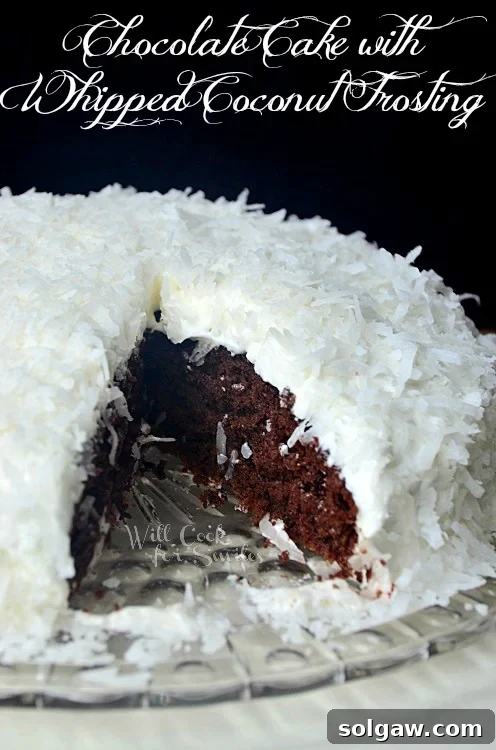 A full chocolate coconut cake with one slice removed, showcasing the moist interior and fluffy frosting, served on a glass plate.