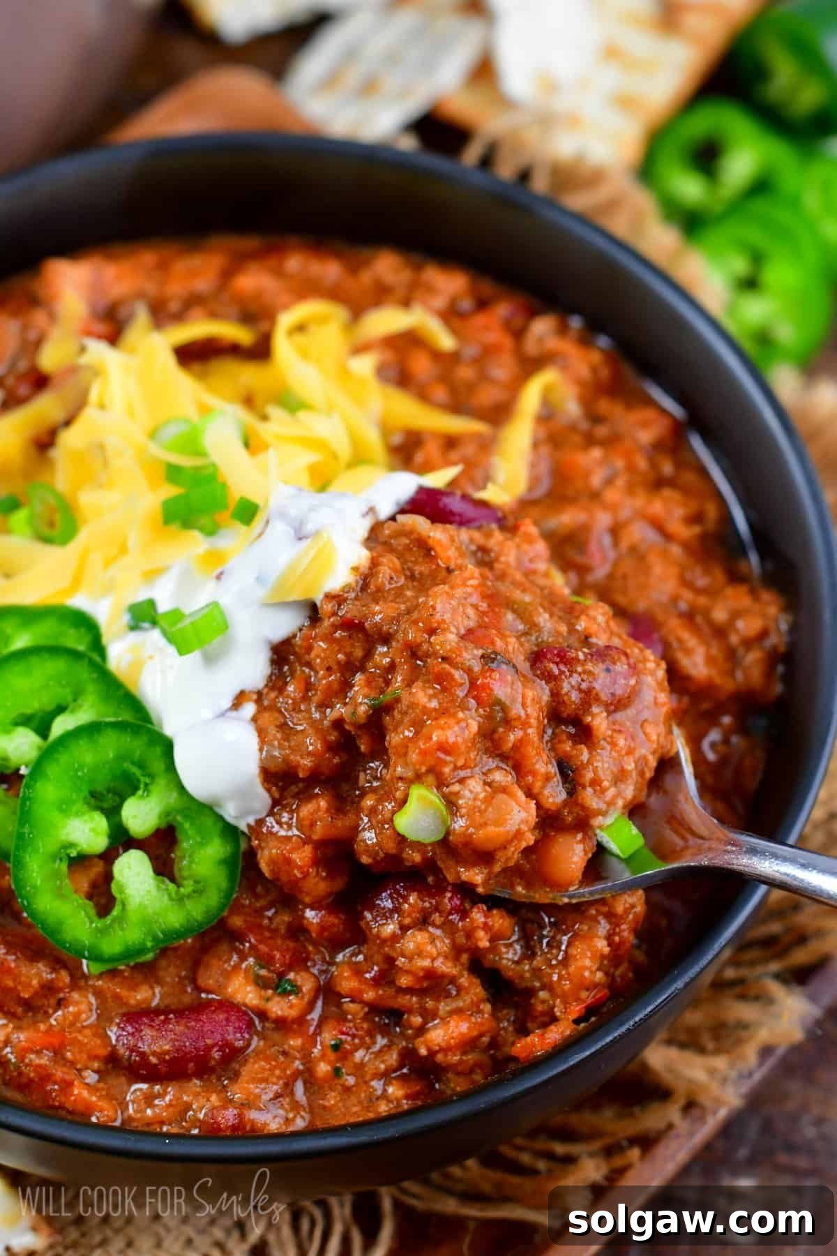 scooping out some beef chili from the bowl with a spoon.