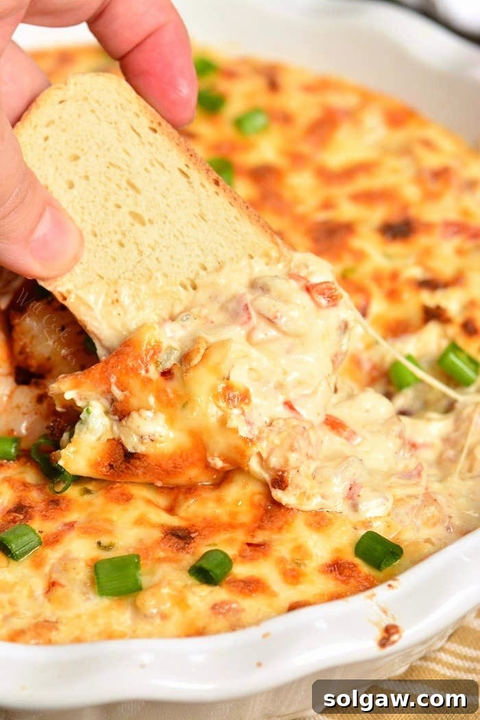 Shrimp Dip in a baking dish with crusty bread dipping some out