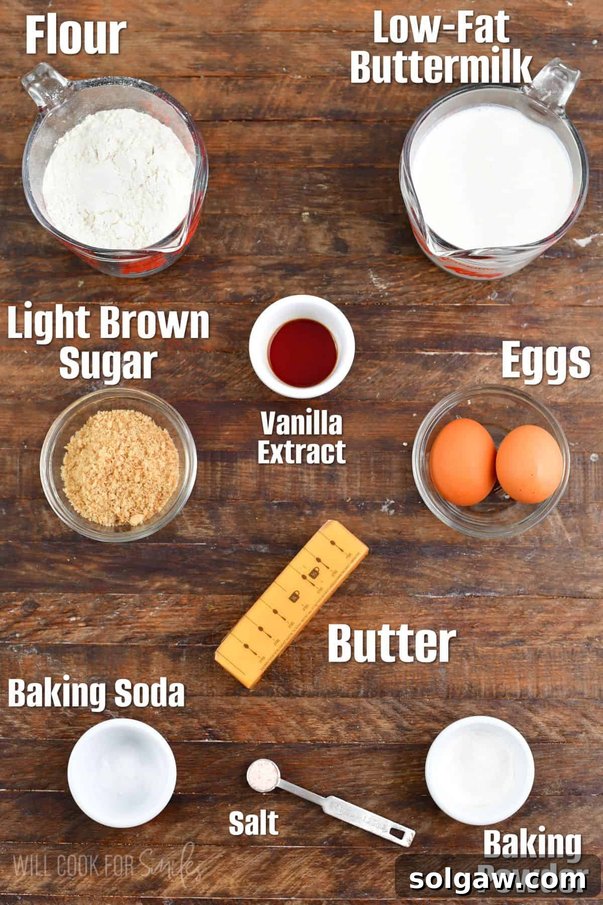 Ingredients for homemade buttermilk waffles laid out in measuring cups on a wooden background, ready for mixing.