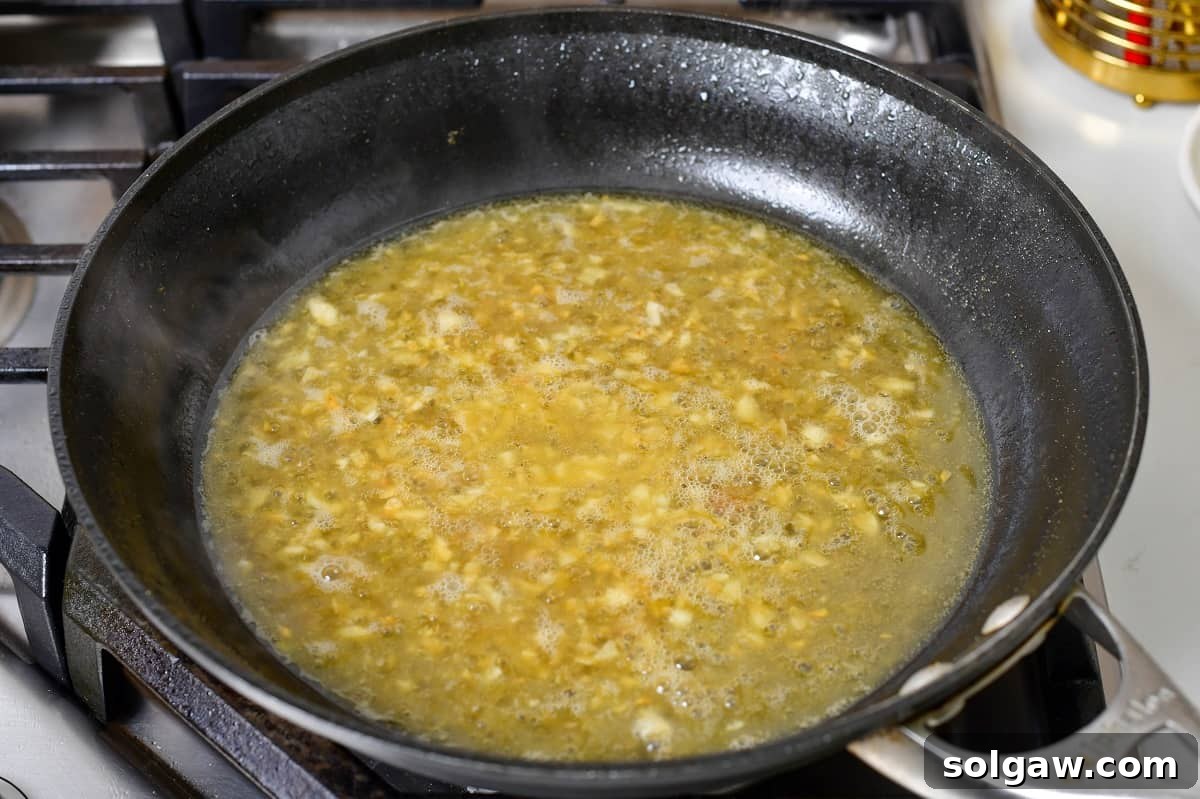 The lemon-butter sauce gently simmering in the pan, reducing and thickening to perfection.