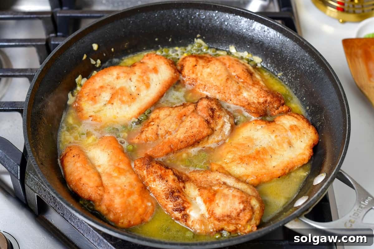 Seared chicken cutlets nestled back into the rich piccata sauce, finishing cooking and absorbing the flavors.