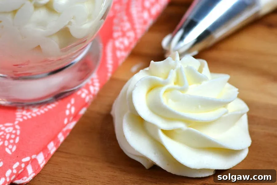 Whipped cream cheese frosting in a bowl with a whisk