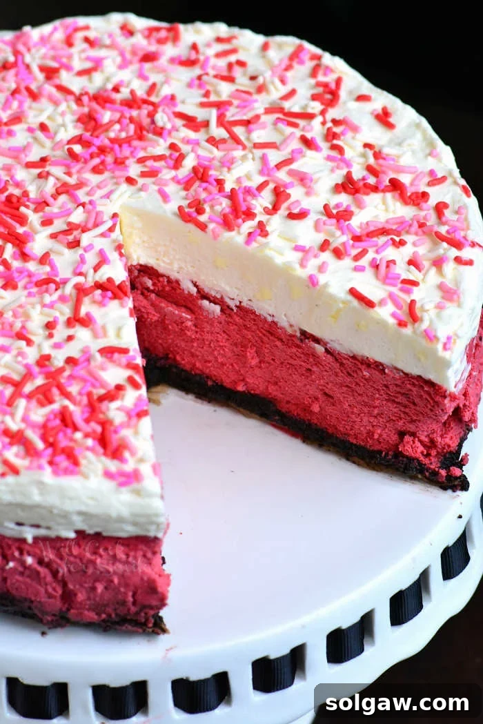 Close-up of a slice of Red Velvet Cheesecake, showing its vibrant color and creamy texture, topped with fluffy cream cheese frosting.