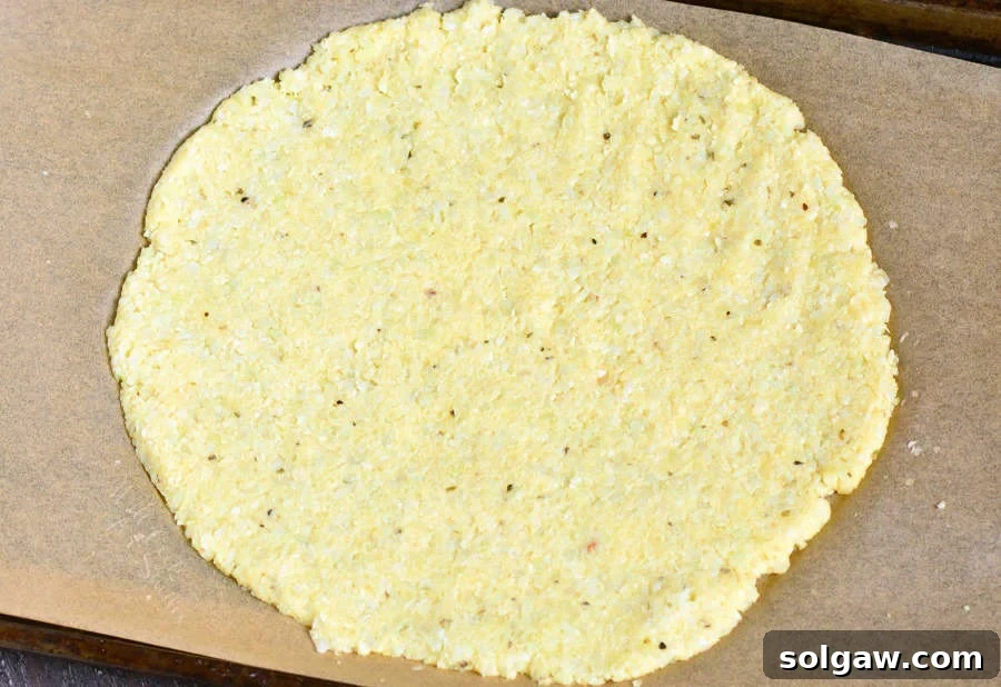 uncooked Cauliflower Pizza Crust on parchment paper