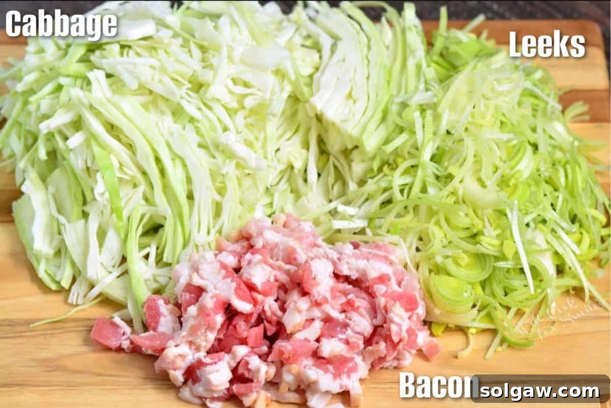 Neatly arranged ingredients for fried cabbage: a head of green cabbage, fresh leeks, and a package of thick-cut bacon on a rustic wooden surface.