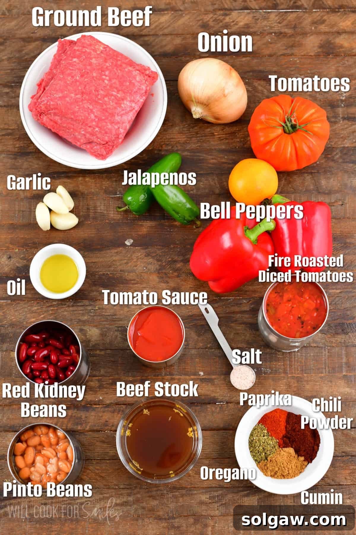 Labeled ingredients for Instant Pot chili, including ground beef, diced tomatoes, beans, onions, bell peppers, jalapeños, garlic, and various spices, laid out on a rustic wooden surface.