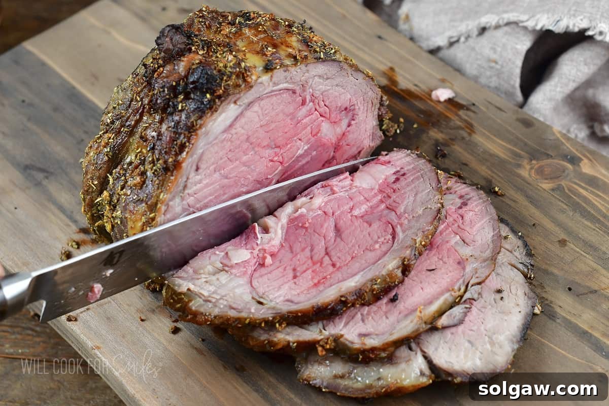 slicing prime rib roast in a cutting board, revealing its medium-rare interior.